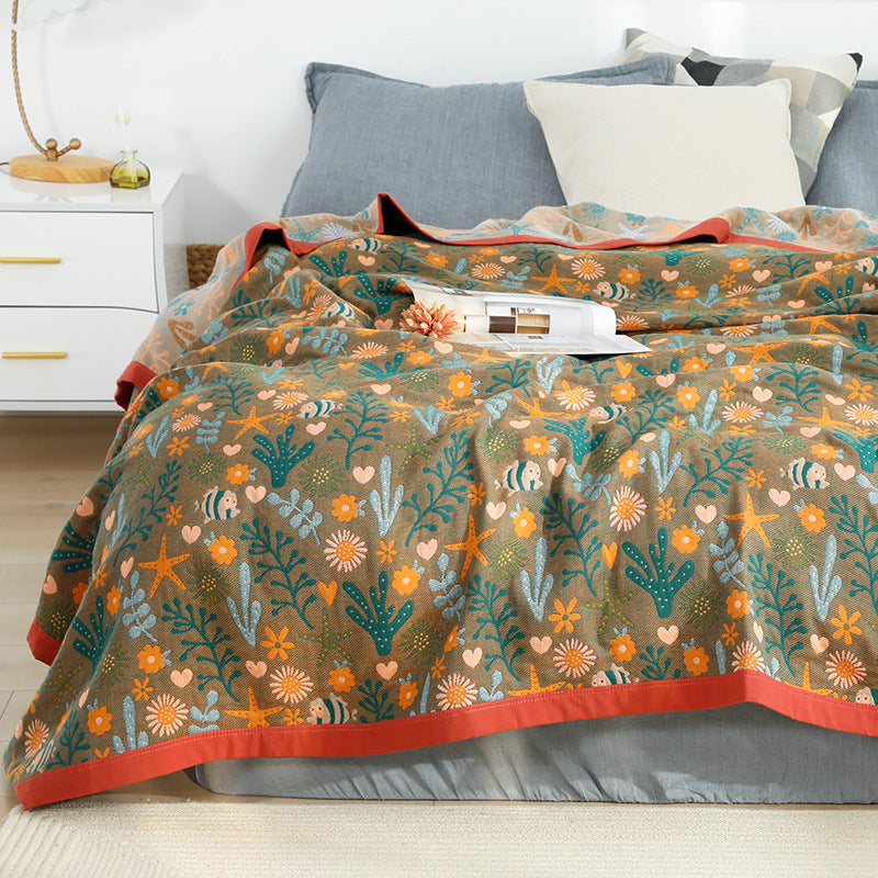 Soft and lightweight cotton gauze-style jacquard throw blanket in brown, featuring a playful marine life pattern of fish and starfish.