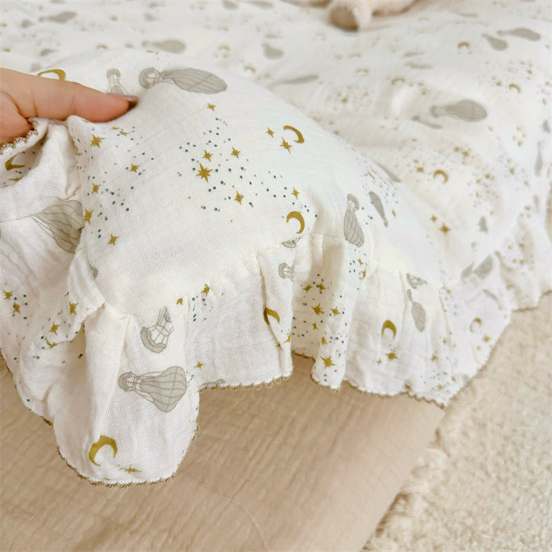 Hand holding the ruffled edge of the cotton gauze duvet cover, showing the hot air balloon and gold celestial print.