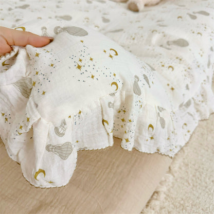 Hand holding the ruffled edge of the cotton gauze duvet cover, showing the hot air balloon and gold celestial print.