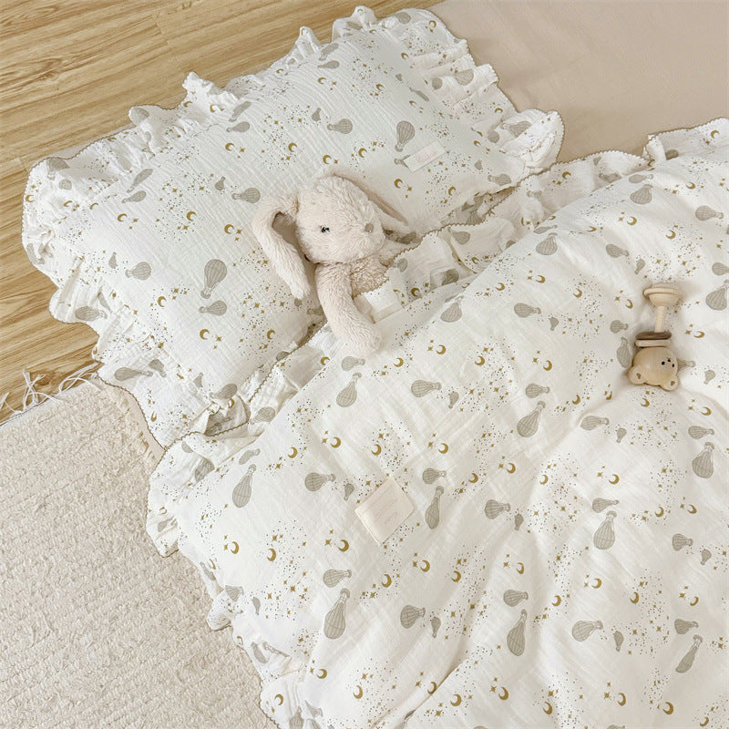 Close-up of the cotton gauze duvet and ruffled pillow sham with a hot air balloon print and stuffed bunny toy.