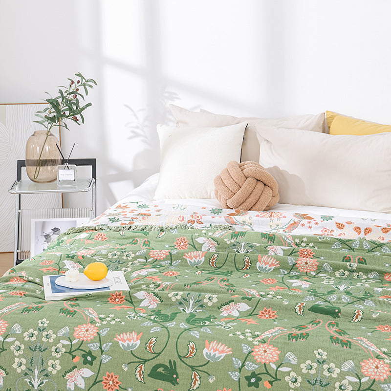 Decorative green cotton throw styled on a bed with pillows, showcasing the breathable material and cozy aesthetic suitable for bed or sofa use.