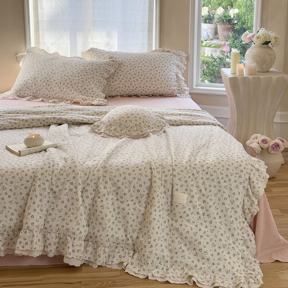 Elegant ruffled floral comforter in breathable cotton gauze, layered over a muted pink bedspread