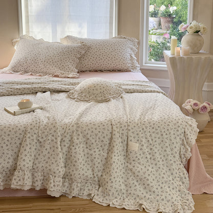 Elegant ruffled floral comforter in breathable cotton gauze, layered over a muted pink bedspread