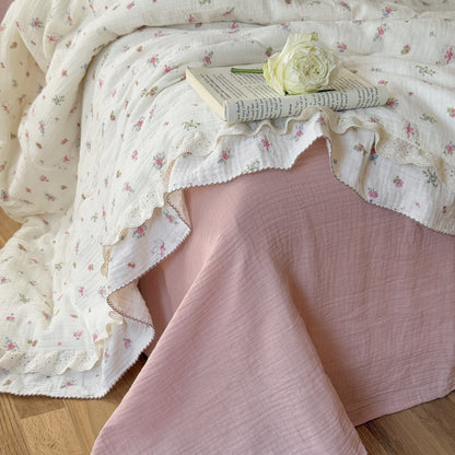 Side view of floral cotton comforter with ruffled lace trim