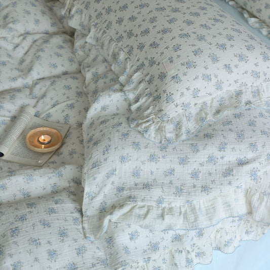 A close-up shot of a blue floral cotton muslin bedding set, showing the soft texture and detailed blue flower print. 
