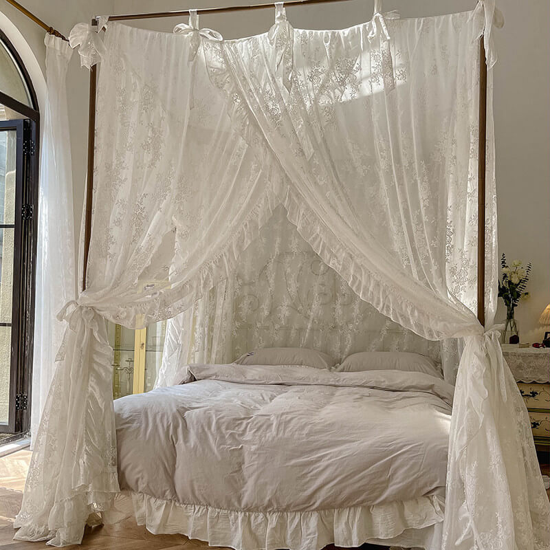 Elegant 4-poster bed with white floral lace ruffle canopy curtains in a bright cozy bedroom