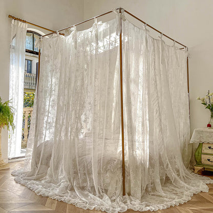 Elegant 4-poster bed with floral lace ruffle canopy curtains in bright, airy bedroom