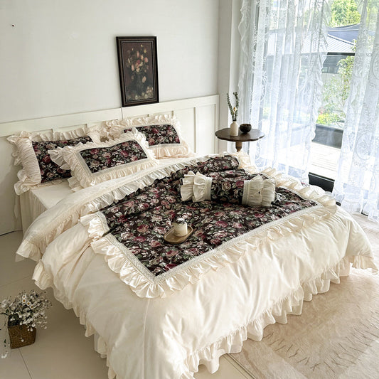 Vintage French Rose cotton bedding set, dark floral print with ruffled ivory sheets and lace trim in a cozy bedroom.