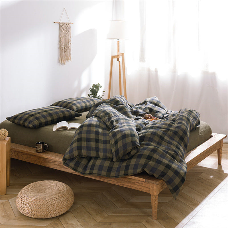 Wide shot of the gauze plaid cotton bedding set in army green, showing the full bedding on the wooden bed frame in a bright room setting.