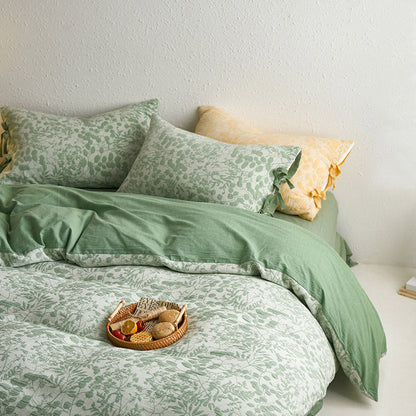 Side view of green botanical jacquard bedding set styled with yellow and green pillows