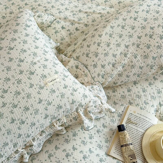 An overhead close-up of a Pastel Blossom Muslin Duvet Cover Set pillow and duvet, showing the delicate floral print on the Cotton Gauze Bedding.