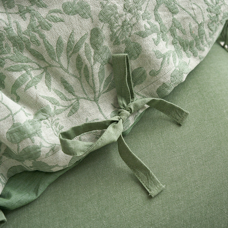 Detail of green jacquard duvet cover tie and woven leaf pattern on cotton gauze