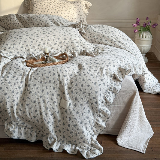 Grey floral duvet cover with ruffle details, arranged on a bed with a matching pillow and solid color flat sheet.