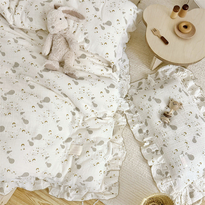 Overhead view of kids' cotton gauze bedding with hot air balloon and celestial print and ruffle trim.