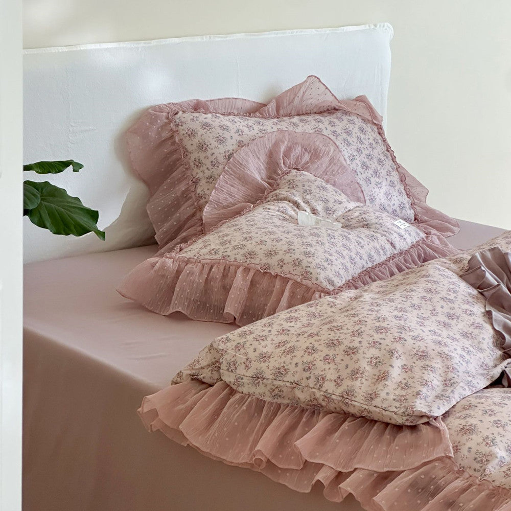 Close-up of the lavender floral ruffled pillows (against the wall): Two floral pillows rest on a solid lavender sheet near a white headboard, capturing the soft folds of the ruffles and the light texture of the cotton gauze fabric.