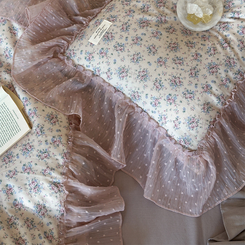 Texture close-up of the floral cotton gauze and ruffle: Extreme close-up shot of the delicate small floral pattern on the duvet cover and the sheer pink dotted tulle ruffle detail.