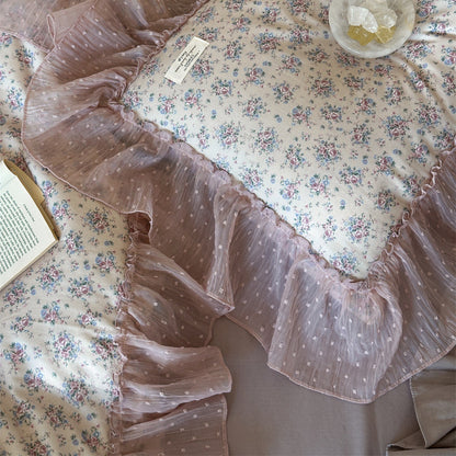 Texture close-up of the floral cotton gauze and ruffle: Extreme close-up shot of the delicate small floral pattern on the duvet cover and the sheer pink dotted tulle ruffle detail.