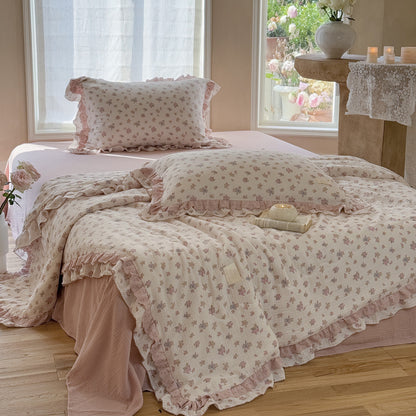 vintage rose floral comforter with ruffles and blush pink flat shee on bed