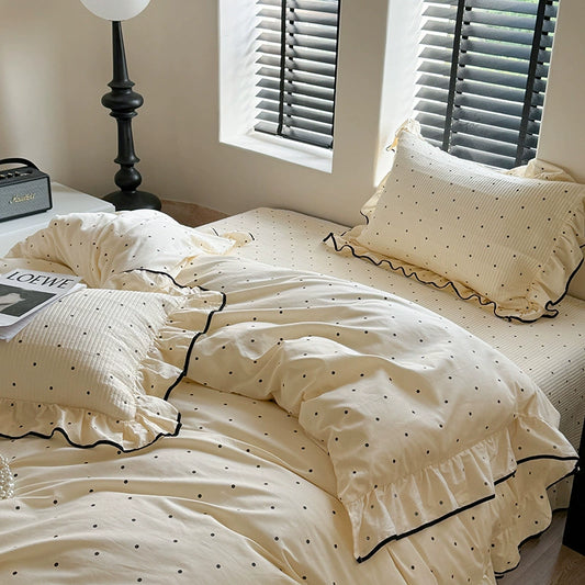 Cream White Polka Dot Ruffled Duvet Cover and Quilted Pillow Set. Full view of the crumpled, cozy-looking duvet set with black polka dots and ruffles, indicating a lightweight and soft feel.