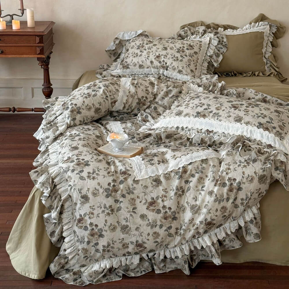 Romantic vintage floral bedding set with olive backing fabric, lace-trimmed pillows, layered ruffles, and warm wooden floor styling