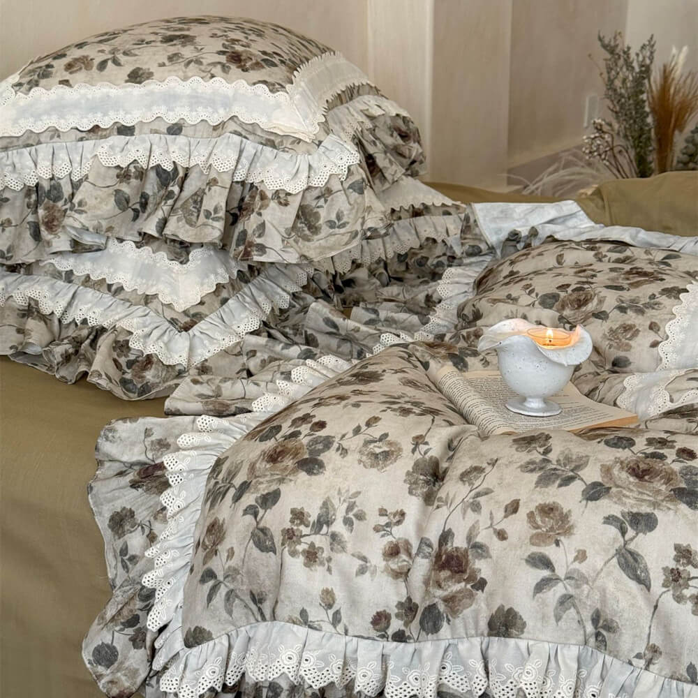 Detailed view of vintage floral bedding with layered ruffle edge, ivory lace trim, olive bed skirt, and soft cotton muslin texture