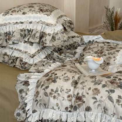 Detailed view of vintage floral bedding with layered ruffle edge, ivory lace trim, olive bed skirt, and soft cotton muslin texture