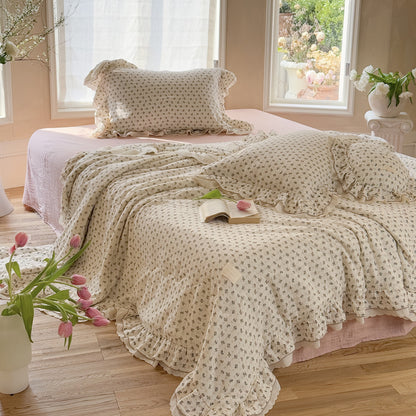 Gauze comforter with pink roses and ruffled edge on wooden floor