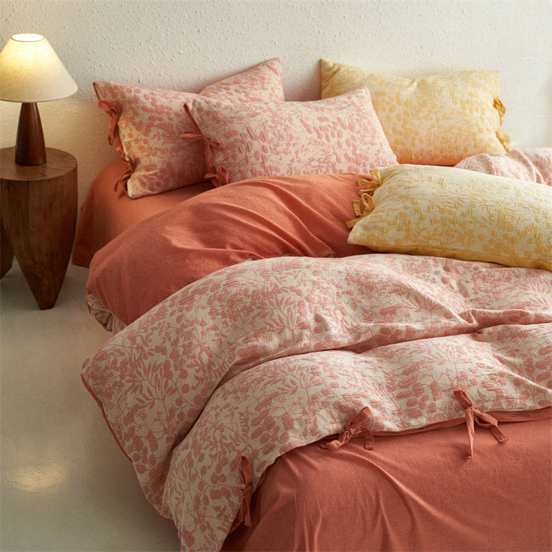 Angled view of blush pink jacquard bedding set styled with yellow pillows