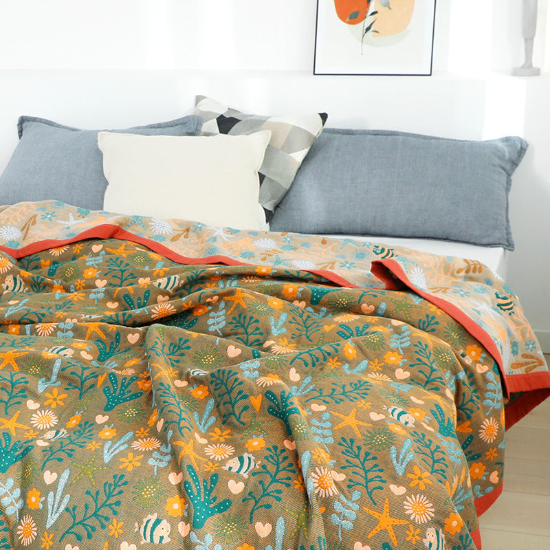 Reversible cotton jacquard throw blanket showing both the teal and brown sides of the underwater garden design on a modern bed.