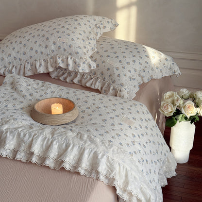 Ruffled cotton comforter styled on bed with vintage rose print