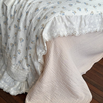 Side view of rose floral cotton gauze comforter with double ruffles and blush pink sheet