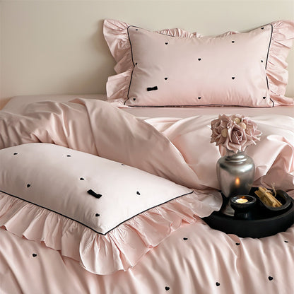 Close-up of pink duvet cover with heart embroidery and ruffle trim