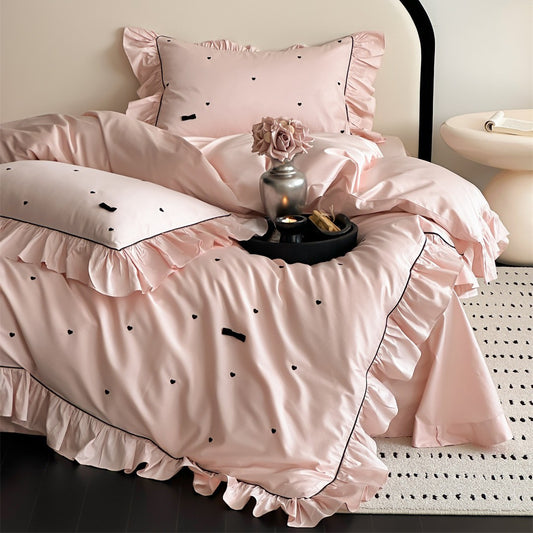 Main view of pink ruffled bedding set with black embroidered hearts