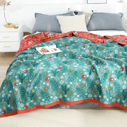 Full bed display of the teal ocean themed throw blanket, styled with gray pillows for a modern coastal bedroom aesthetic.